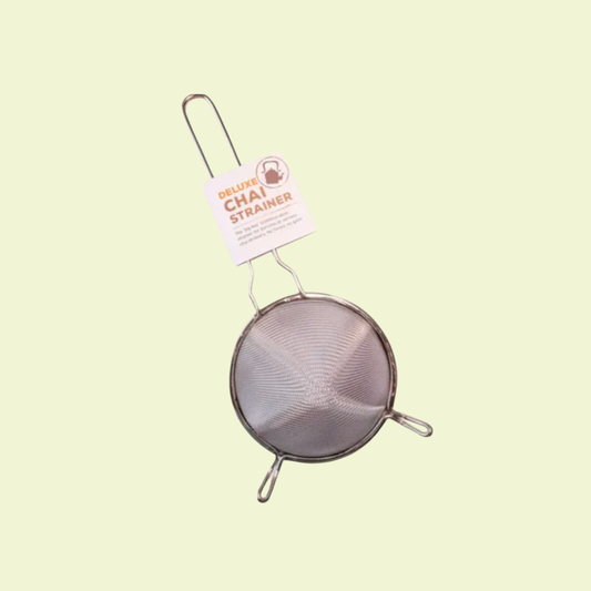 Metal chai strainer with a label on a light green background