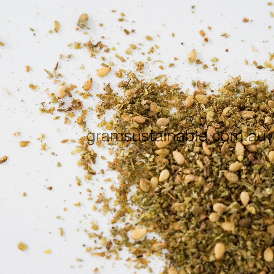 A close-up of zaatar spices including sesame seeds, sumac, thyme, and salt, with a visible 'gramsustainable.com' text overlay.